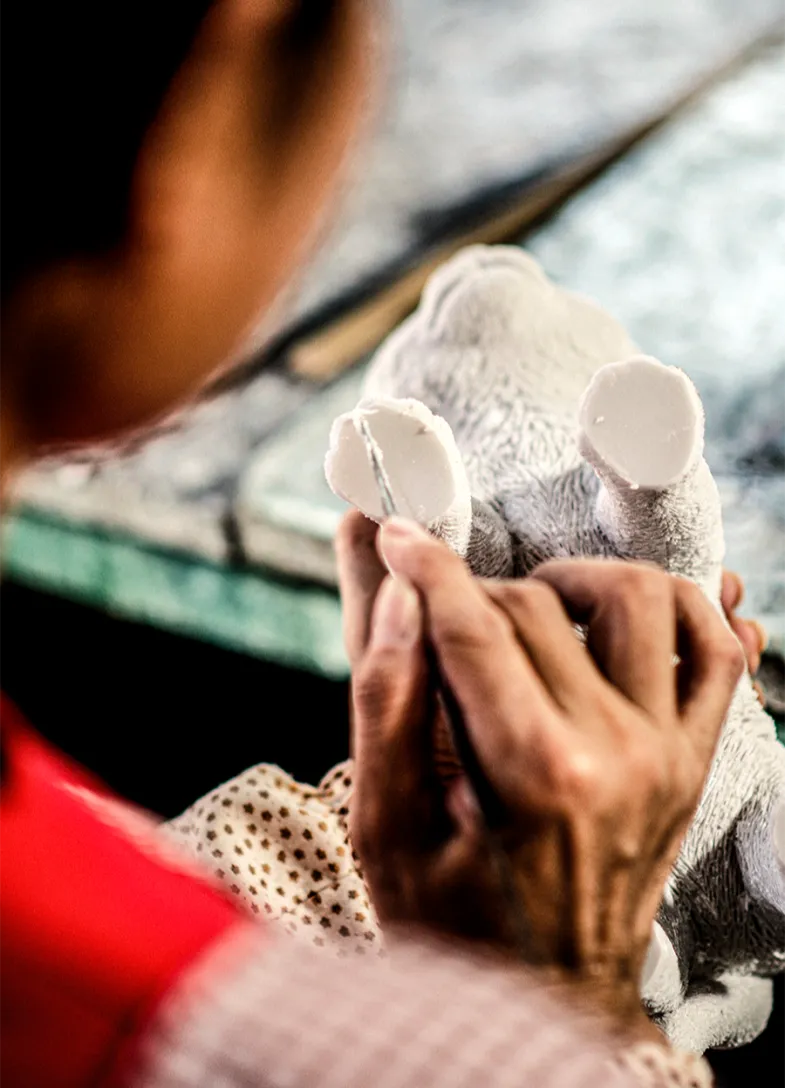 Woman trims resin from the feet of a cat figurine
